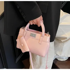 Detail of pink glossy patent leather handbag with silver twist lock and mini charm bag