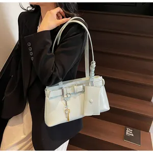 Detail view of mint green shoulder bag with small pouch and key charm on wood stairs