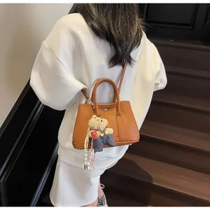 Brown lychee leather bucket bag with top handles and a cute bear bag charm accessory