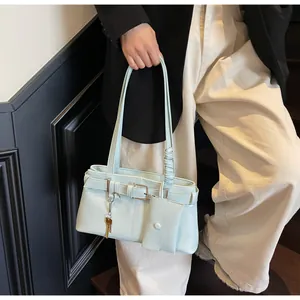 Detail of light green baguette bag with decorative buckle, mini pouch, and key charm