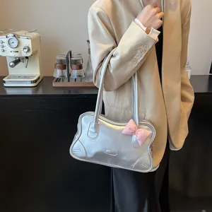 Silver metallic tote bag with pink bow accent for women shown on model in cozy cafe setting