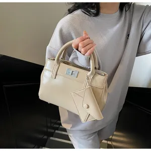 Detail of elegant beige faux leather handbag with silver square clasp and mini pouch