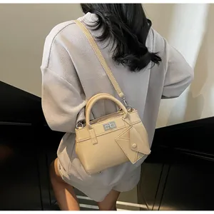 Detail of a beige handbag with a silver twist lock and a matching small envelope charm