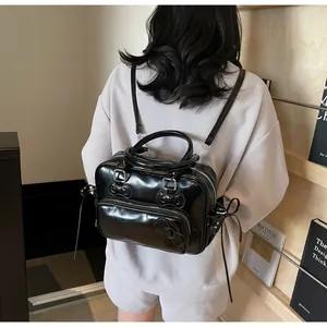 Detail view of the black glossy pillow backpack with a 3D bow on a model's back