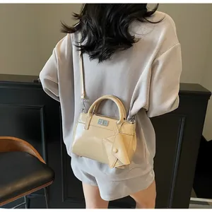 Model view showing the scale and styling of a beige polished satchel with charm