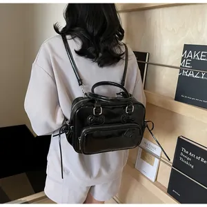 Detail of glossy black backpack with bow accents, worn in a cozy lifestyle setting