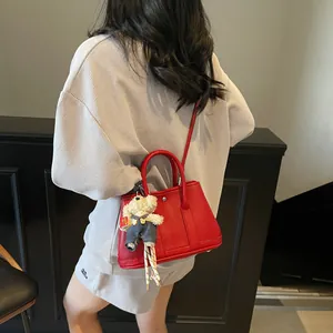 Red lychee pattern leather bucket bag with teddy bear charm shown worn as a crossbody bag