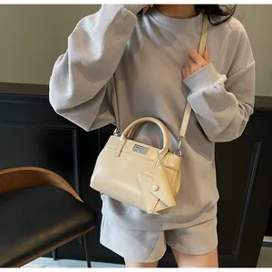 Detail of beige shoulder bag with silver turn-lock and envelope-style charm