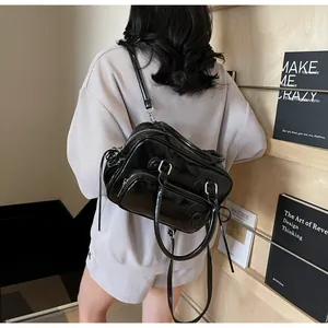 Rear view of a model wearing a shiny black multi-pocket Y2K crossbody bag in a studio set