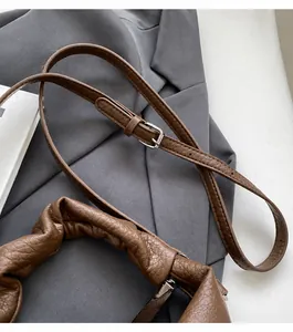 Detail of brown lychee leather bag with adjustable shoulder strap and pleated handle