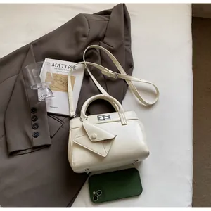 Detail of cream crossbody bag with silver twist lock and envelope charm on fabric