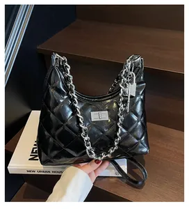 Detail of black quilted hobo bag with silver chain strap and metal lock closure