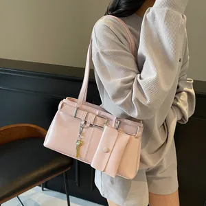 Pink moto-style shoulder bag with decorative buckles and small coin purse charm