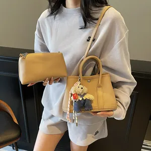 Minimalist khaki lychee grain leather bucket bag set with teddy bear charm and crossbody strap