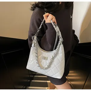 Detail of white quilted hobo bag featuring silver chain and metallic turn-lock closure