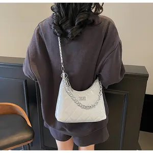 Detailed view of a white quilted leather shoulder bag with silver chain and metal clasp