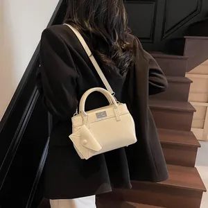 Creamy white handheld crossbody bag for women with metal lock shown in lifestyle setting