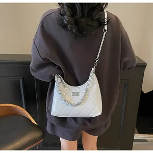 Detail of white quilted patent leather bag with silver chain and metal turn-lock closure