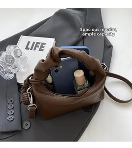 Close-up of brown textured leather bag interior holding phone, lipstick and perfume