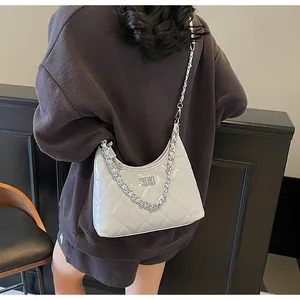Detail of light grey quilted bag with shiny leather, silver turn-lock and chain handle