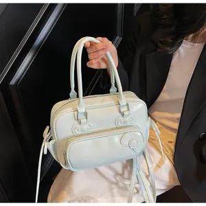 Close-up of pale green handbag with decorative 3D bows and sleek zipper pockets