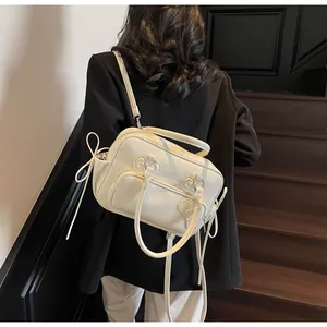 Detail of cream multi-functional bag with bow drawstring and silver hardware