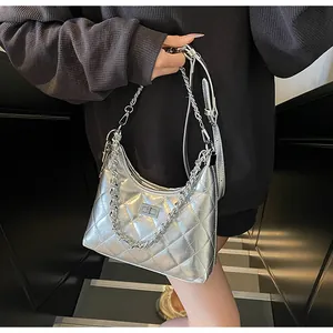 Detailed view of silver quilted shoulder bag with chain strap and twist lock on model
