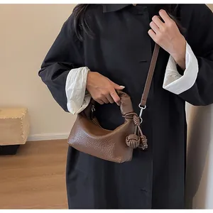 Detail of a brown leather dumpling bag featuring a unique knotted handle and silver hardware
