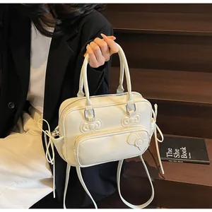 Detail of cream white pillow bag featuring 3D bow accents and side drawstring elements