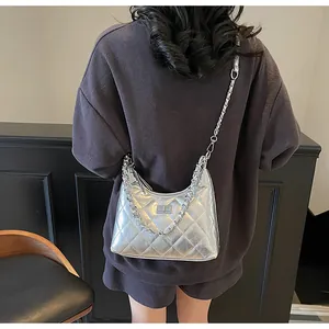 Detail of silver metallic quilted handbag featuring a bold chain and sleek turn-lock closure