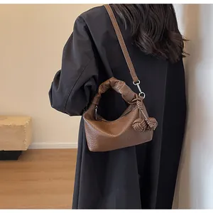 Brown lychee leather shoulder bag with scrunchie handle shown on black coat