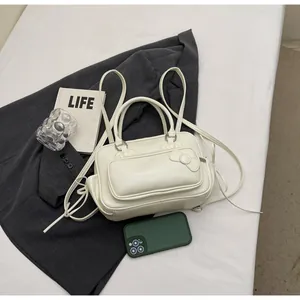 Detail of a white pillow backpack featuring a bow accent and drawstring side details