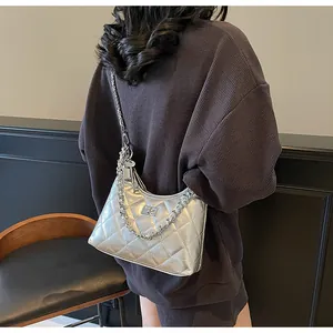 Detail of silver quilted chain bag with metallic finish shown on shoulder in a lifestyle setting
