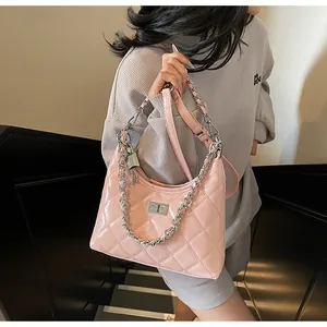 Detail of pink quilted handbag with silver chain and lock on a gray waffle knit outfit