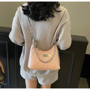 Detailed view of pink quilted crescent bag with silver chain strap and metal clasp