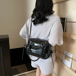 Glossy black pillow bag with bow details worn as a versatile crossbody by a model