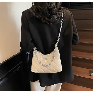 Detail of quilted leather crossbody bag with silver chain and metal turn-lock closure