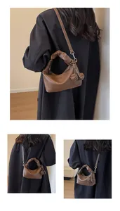 Detail of dark brown leather crescent bag featuring ruched handle and woven side knots