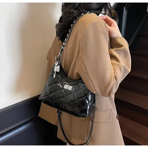 Detail of black quilted shoulder bag with silver chain and lock charms on suit model