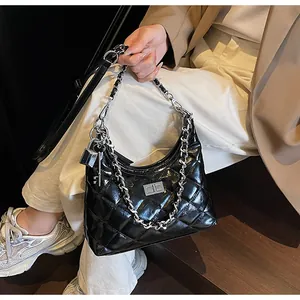 Detail of black quilted leather handbag with silver chain strap and metal lock closure