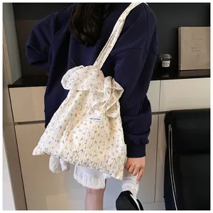 Detail of floral canvas tote bag with ruffled shoulder strap and magic pocket label