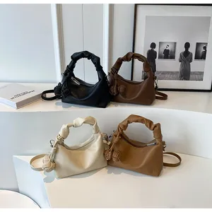 Detail view of stylish dumpling bags in four colors with ruffled handles and charms