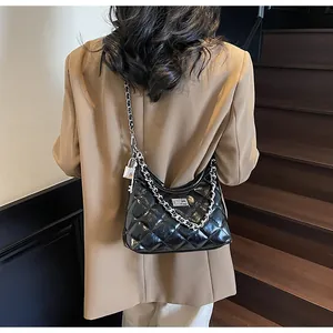 Detail of black quilted patent leather bag with silver chain and padlock charm