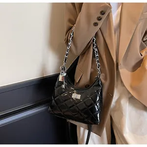Detail of black quilted chain bag with silver padlock charm and high-gloss finish