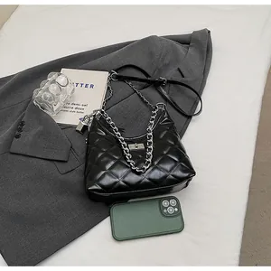 Detail of black quilted leather handbag with silver metal turn-lock and chain handle