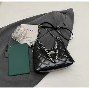 Detail of black quilted shoulder bag featuring silver chain and metal twist lock