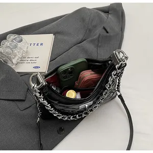 Detail of black quilted shoulder bag featuring silver chain, metal lock and red interior
