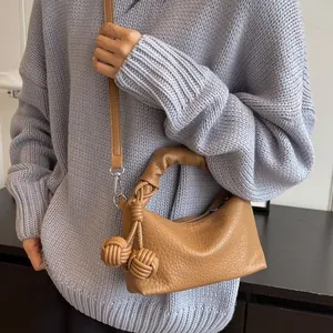 Chic camel leather hobo bag with knotted handle and decorative woven ball pendants