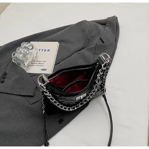 Macro view of black quilted patent leather bag with red interior and silver chain strap