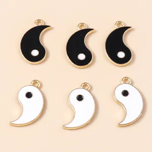 Flat lay of alloy Tai Chi pendants with black and white enamel finish and gold edges